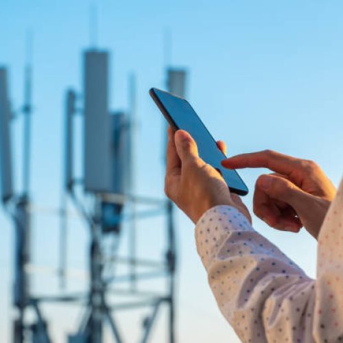 5G communications tower with man using mobile phone